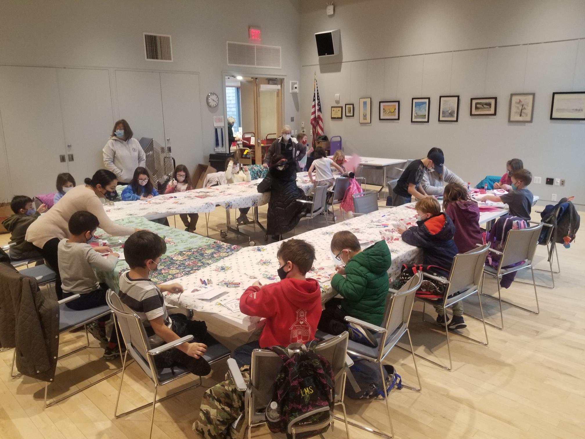 several children at craft tables making Valentine's Day cards